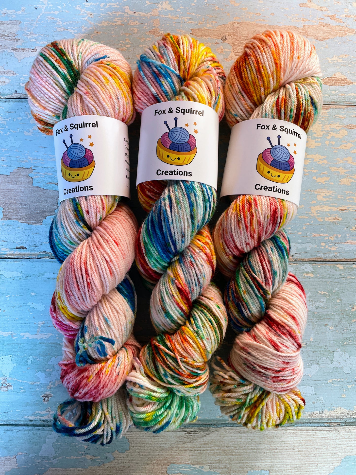 Zoomed in shot of 100g DK weight yarn in colourway Rainbow Sprinkles. This is an undeyd yarn base with layers of speckles in red, yellow, green, blue.