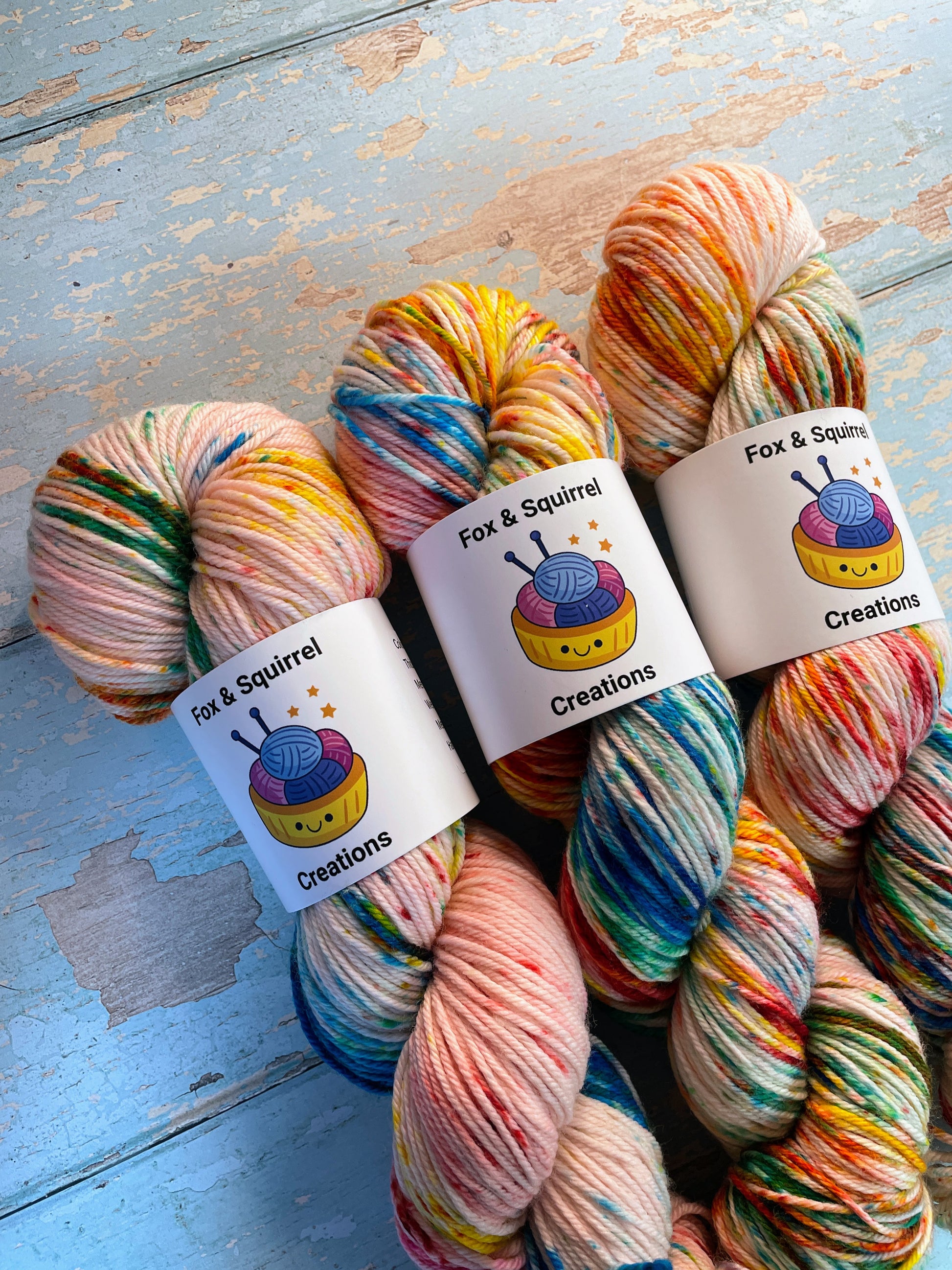 Close up shot of 100g DK weight yarn in colourway Rainbow Sprinkles. This is an undeyd yarn base with layers of speckles in red, yellow, green, blue.