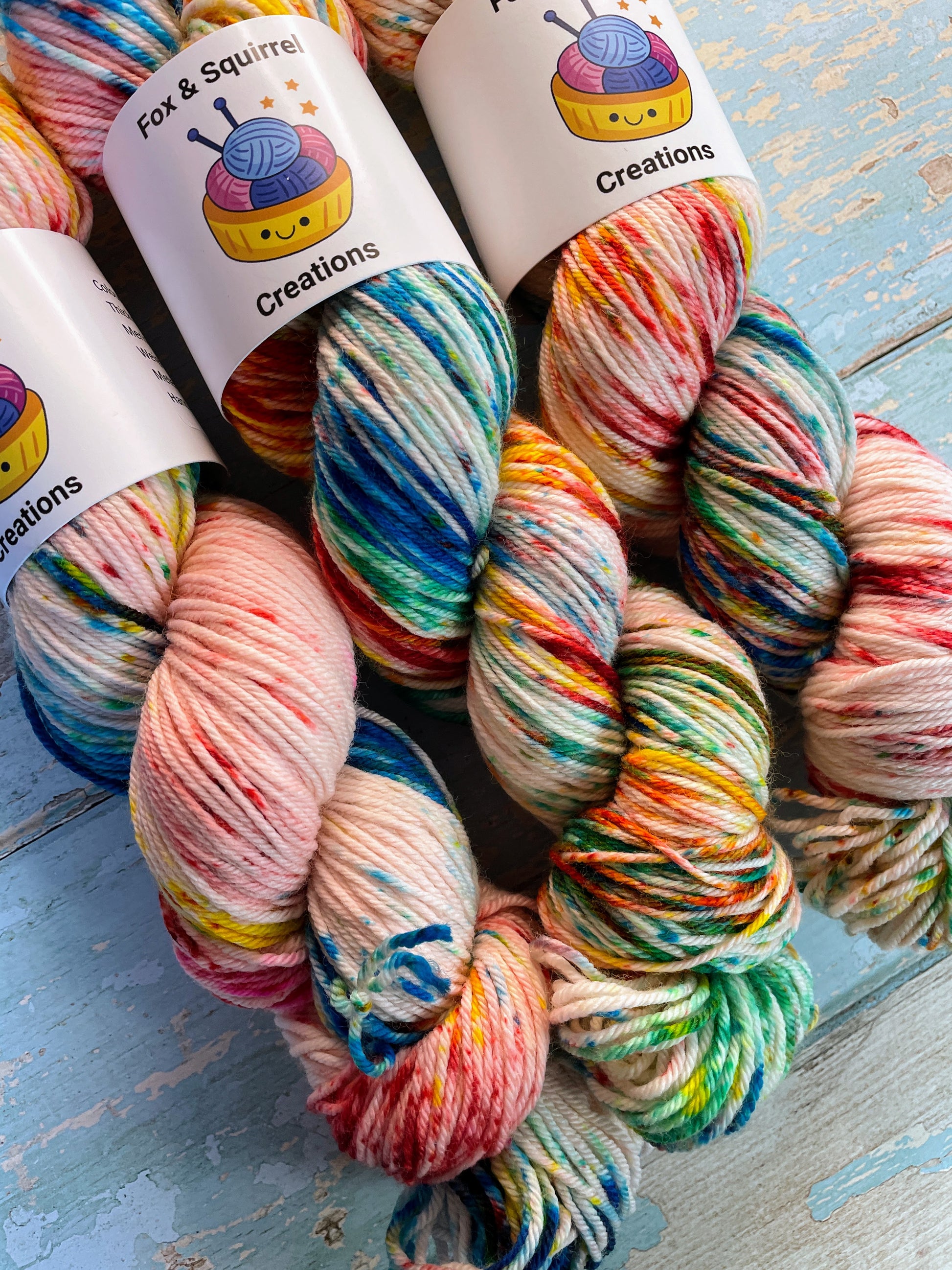 Close up shot of 100g DK weight yarn in colourway Rainbow Sprinkles. This is an undeyd yarn base with layers of speckles in red, yellow, green, blue. This image shows off the intensity of the speckles.