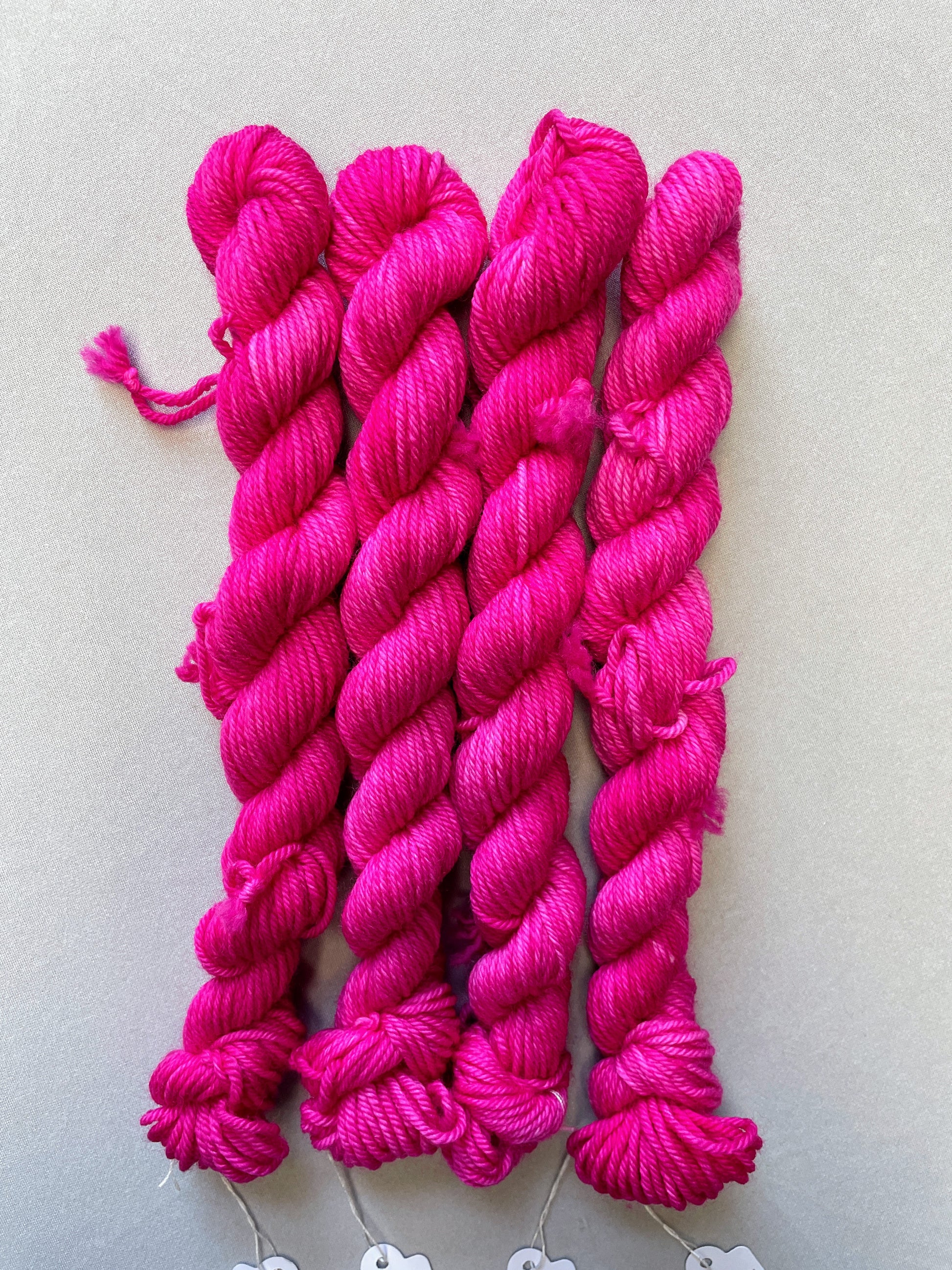 Zoomed in shot of 20g DK weight mini skeins in colourway Pink. A semi-solid colourway in a bright pink shade.