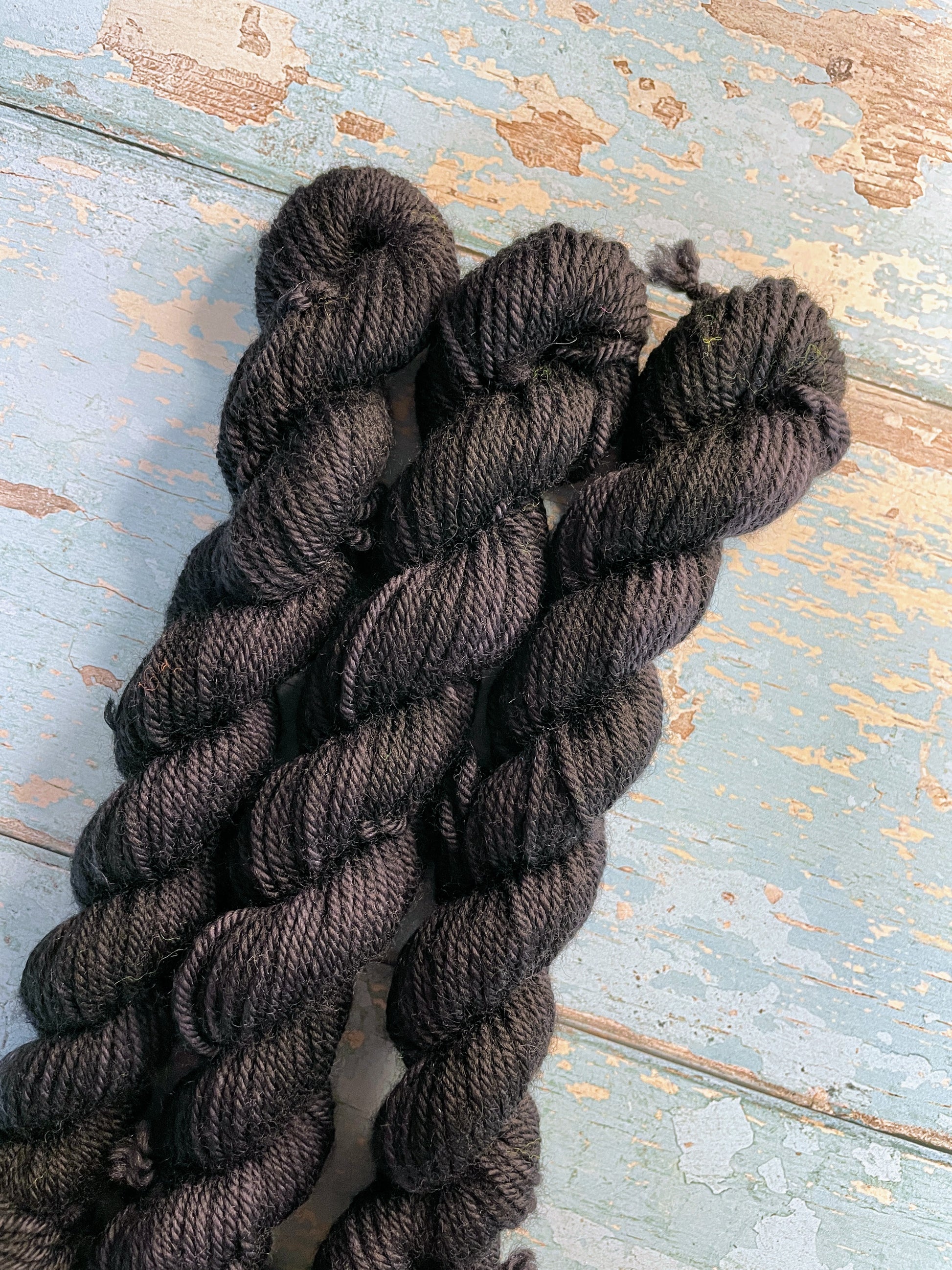 Close up shot of 20g sock weight mini skeins in semi-solid colourway Black. This colourway is a deep, intense Black colour.