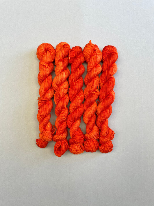 Full shot of Sock weight mini skeins in colourway Lava. This semi-solid colourway is dyed up in a bright, intense orange.