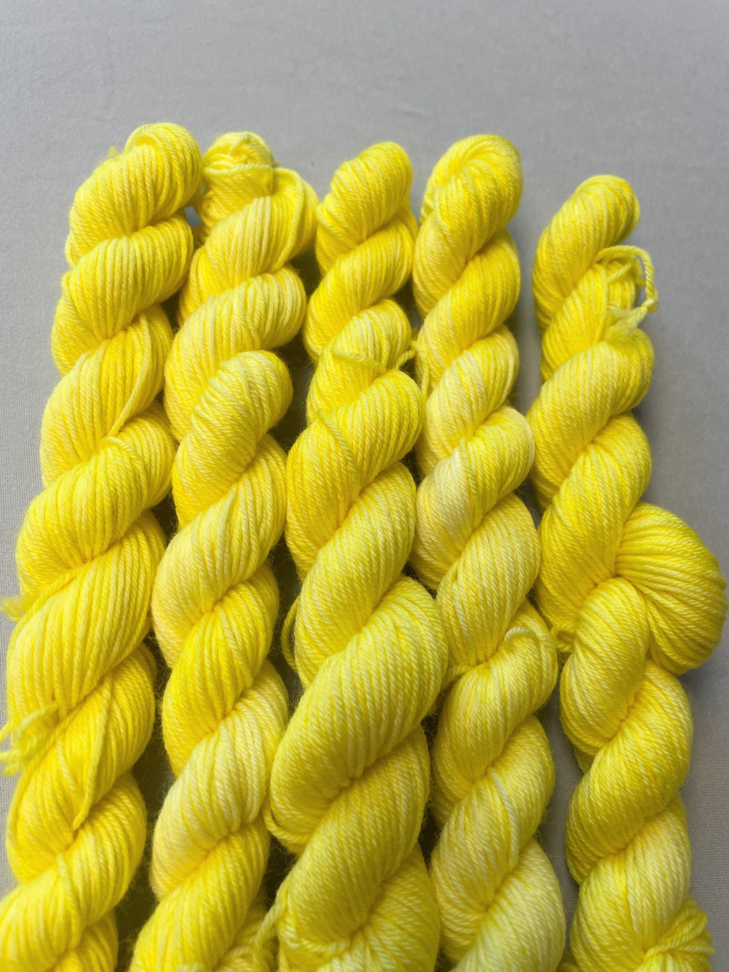 Close up shot of 20g Sock weight mini skeins in colourway Lemon. A semi-solid colourway of pale yellow colour.
