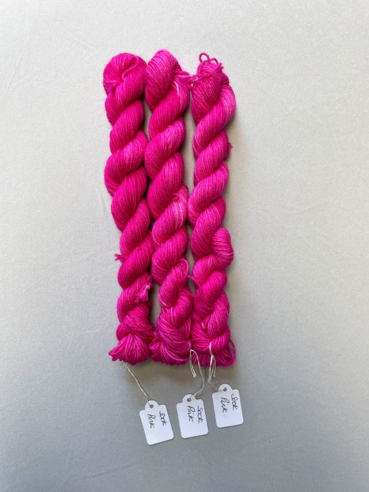 Full shot of 20g sock weight mini skeins in colourway Pink. A semi-solid colourway in a bright pink shade.