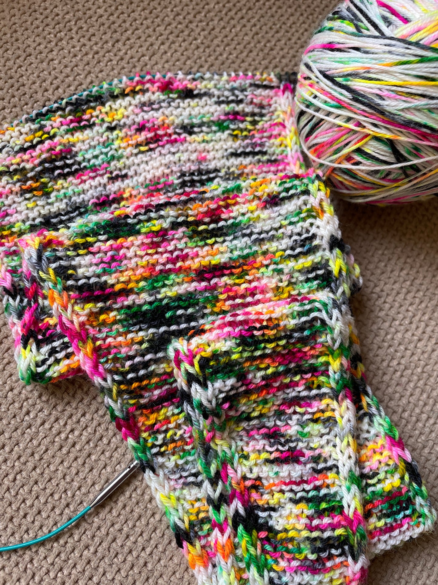 A knitted sample using 100g of Sock weight Punk Rocker. The knitting pattern is a large Sophie Scarf. Also shows the yarn wound into a ball.