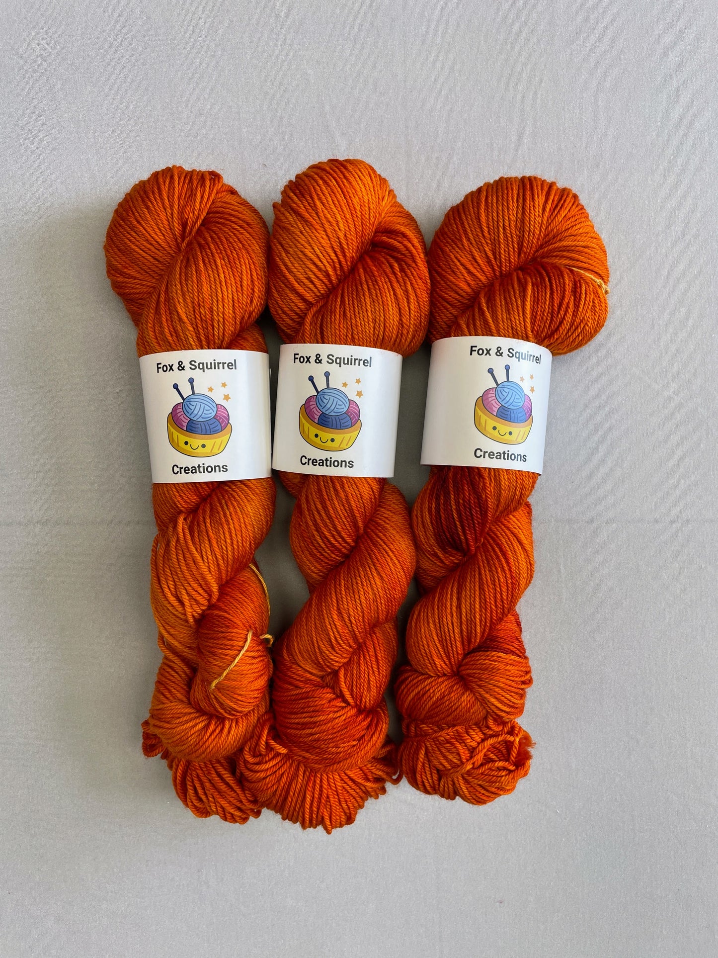 Full shot of 100g DK weight skeins in semi-solid colourway, Saffron. A intense and deep Orange colourway.