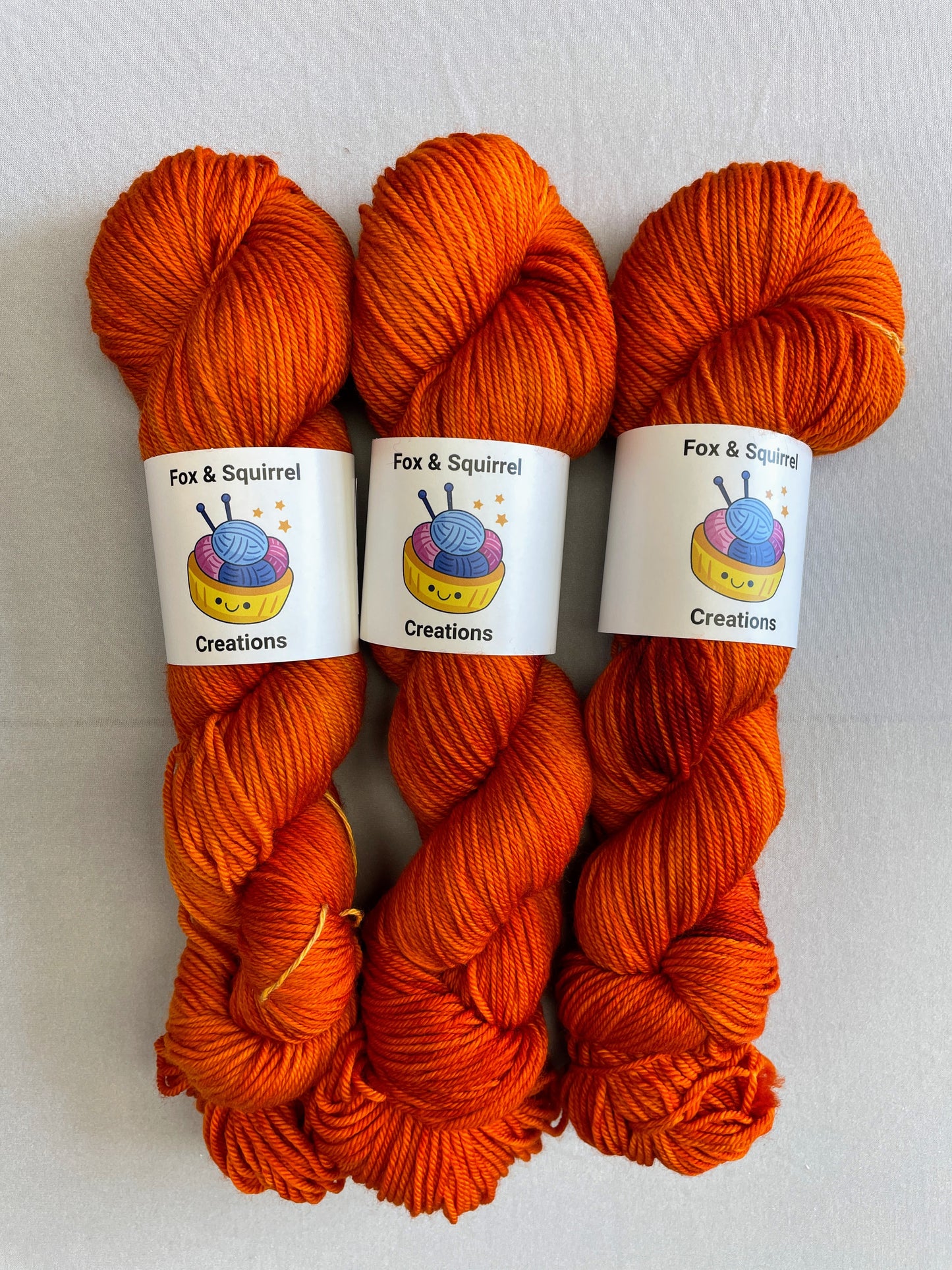 Zoomed in shot of 100g DK weight skeins in semi-solid colourway, Saffron. A intense and deep Orange colourway.