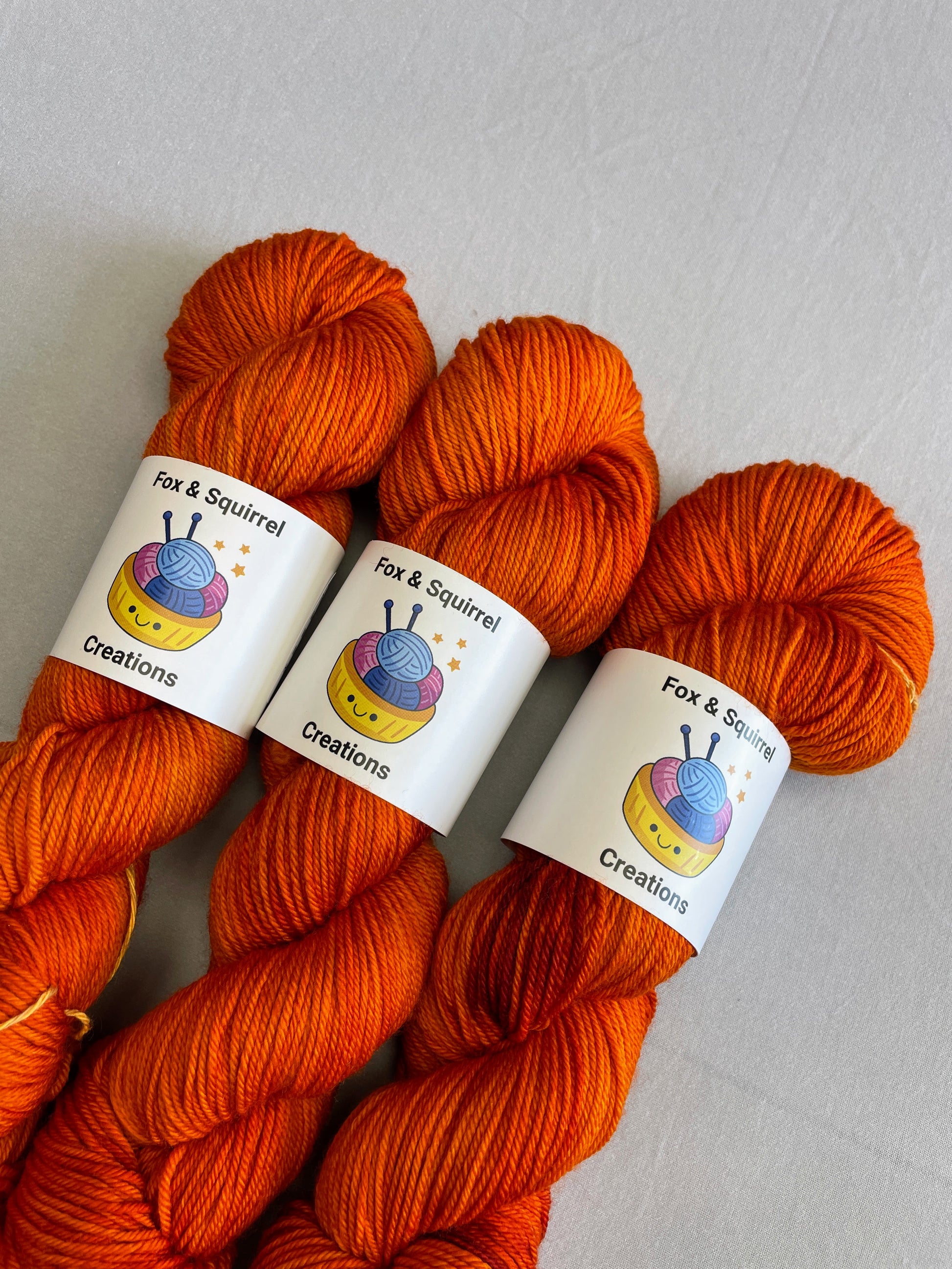 Close up shot of 100g DK weight skeins in semi-solid colourway, Saffron. A intense and deep Orange colourway.