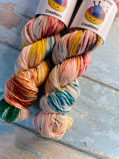 Close up shot of 100g Sock weight yarn in colourway Rainbow Sprinkles. This is an undeyd yarn base with layers of speckles in red, yellow, green, blue. 