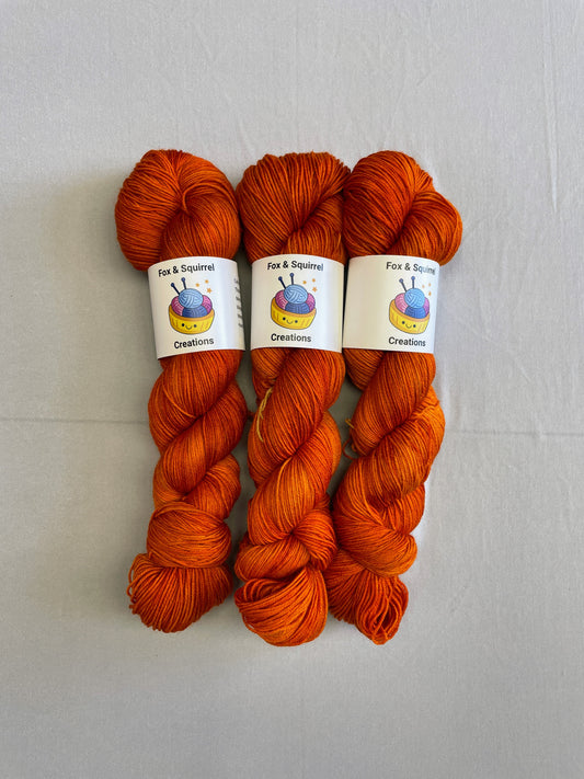 Full shot of 100g sock weight skeins in semi-solid colourway, Saffron. A intense and deep Orange colourway.