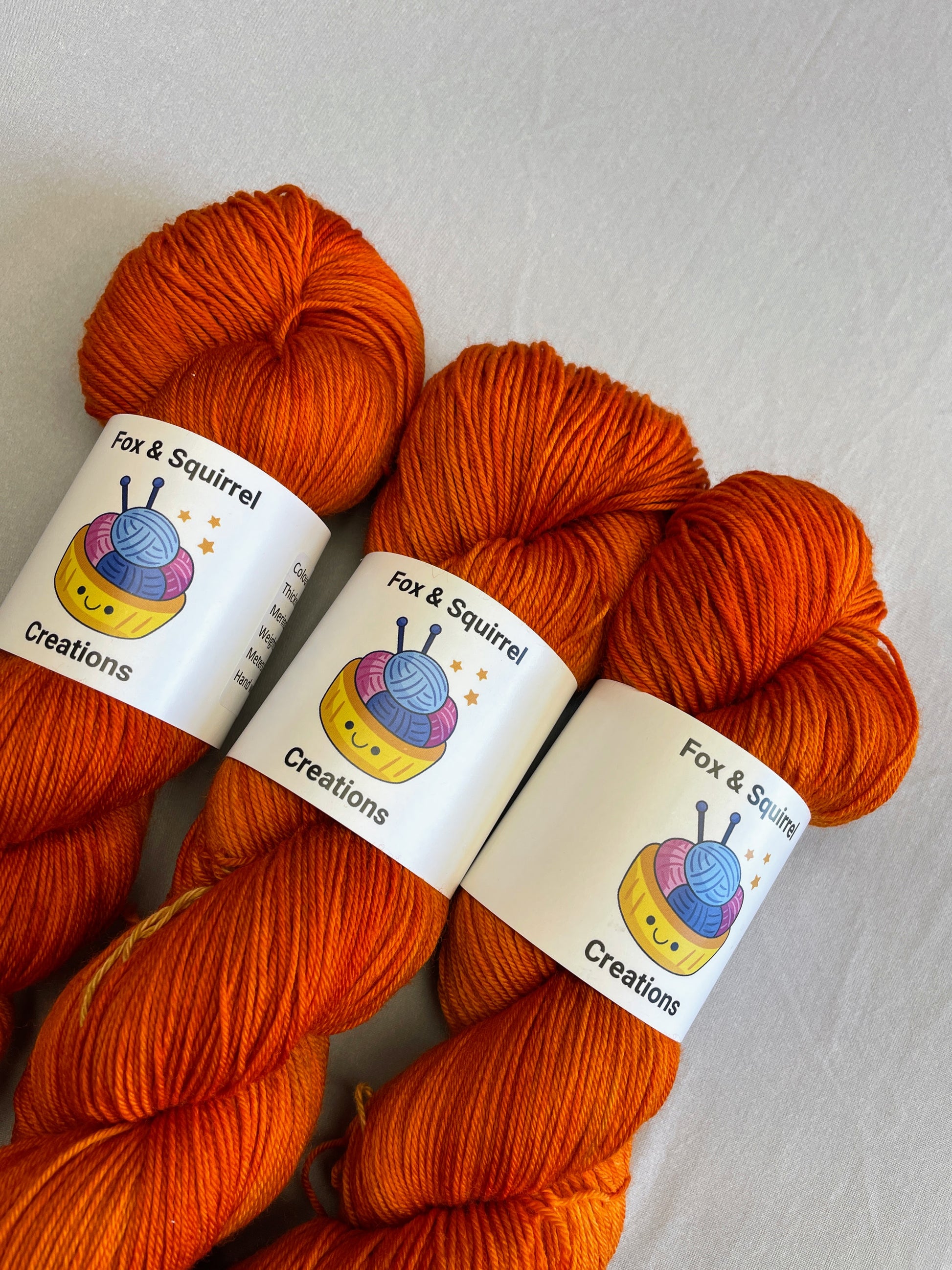 Close up shot of 100g sock weight skeins in semi-solid colourway, Saffron. A intense and deep Orange colourway.