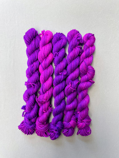 Full shot of 20g DK weigh mini skeins in colourway Electric Purple. This colourway is an intense and bright purple that breaks into Neon Pink. Photographed on light grey background.