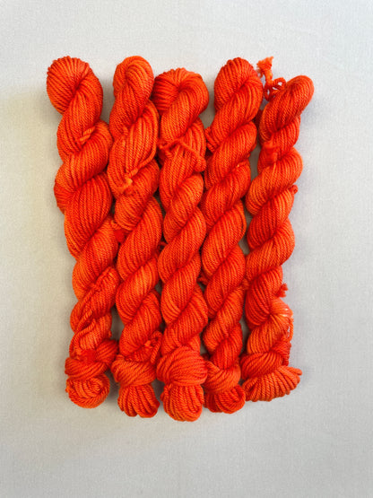 Zoomed in shot of DK weight mini skeins in colourway Lava. This semi-solid colourway is dyed up in a bright, intense orange. 