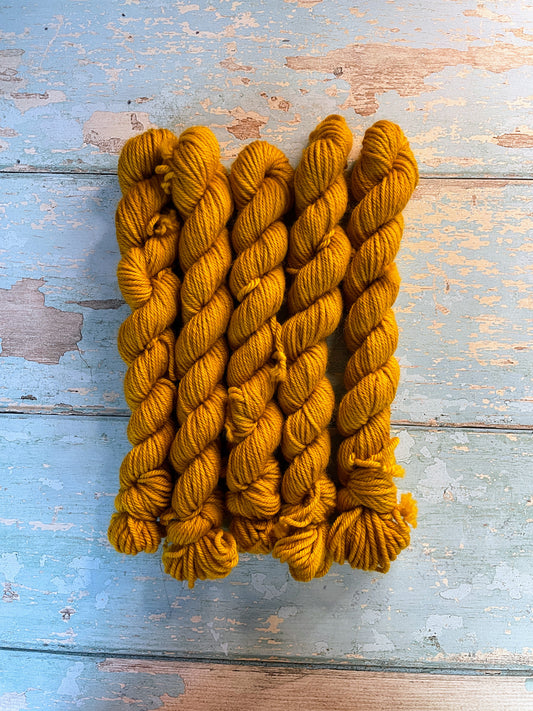 Full shot of DK weight mini skeins in colourway Mustard. This is a semi-solid colourway in a rich, golden mustard colour.