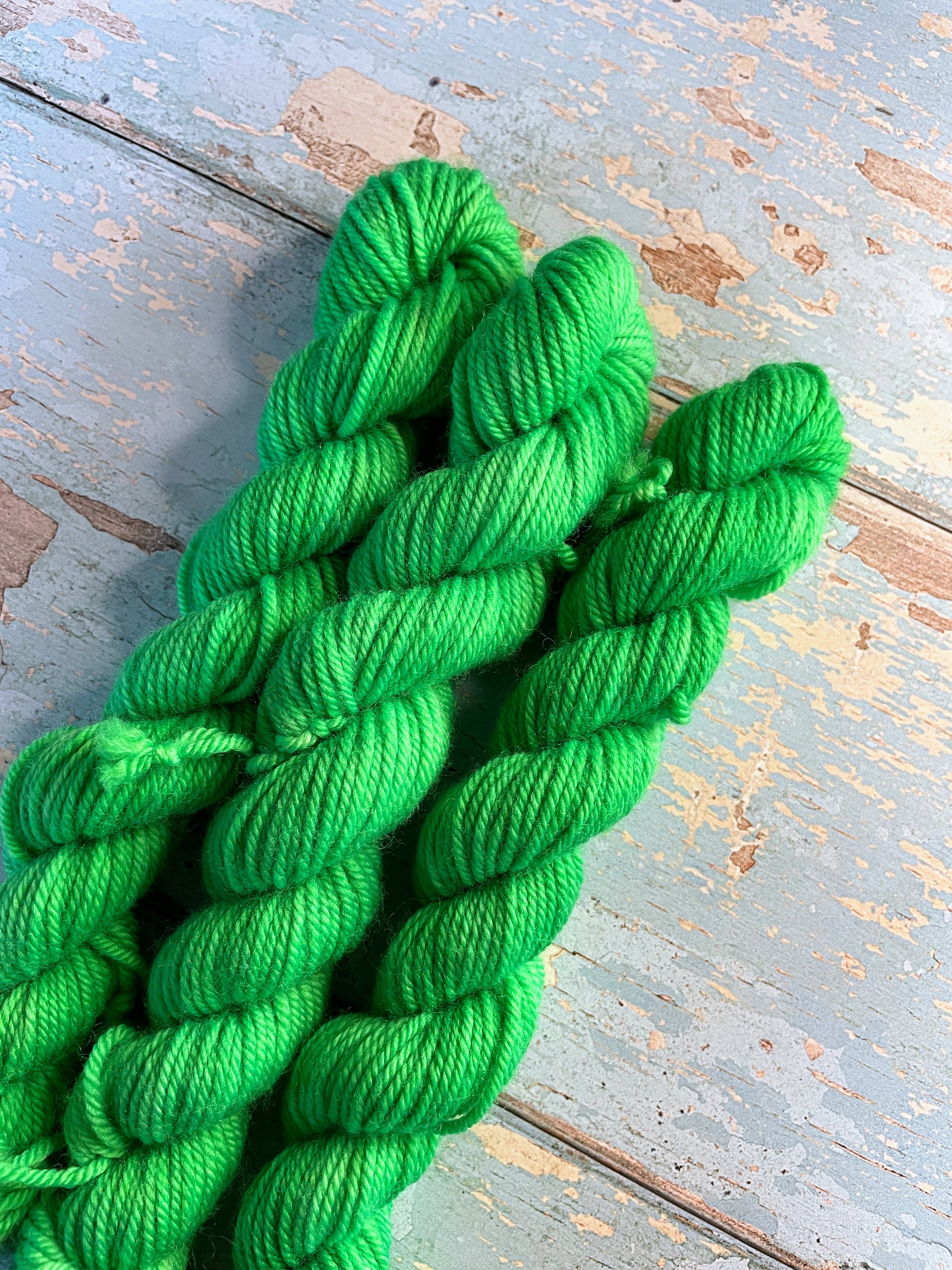 Close up shot of 20g DK mini skeins in colourway Neon Green. This is a semi-solid colourway and will glow under U.V. light.