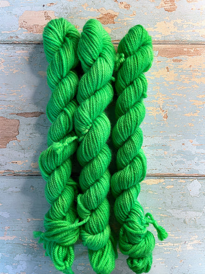 Full shot of 20g DK mini skeins in colourway Neon Green. This is a semi-solid colourway and will glow under U.V. light.