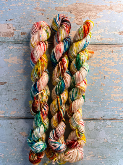 Zoomed in shot of 20g DK weight mini skeins in colourway Rainbow Sprinkles. This is an undeyd yarn base with layers of speckles in red, yellow, green, blue. 