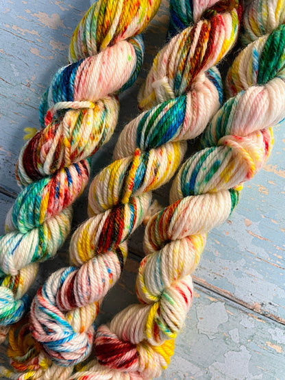 Close up shot of 20g DK weight mini skeins in colourway Rainbow Sprinkles to show off the intense colour of the speckles. This is an undeyd yarn base with layers of speckles in red, yellow, green, blue. 