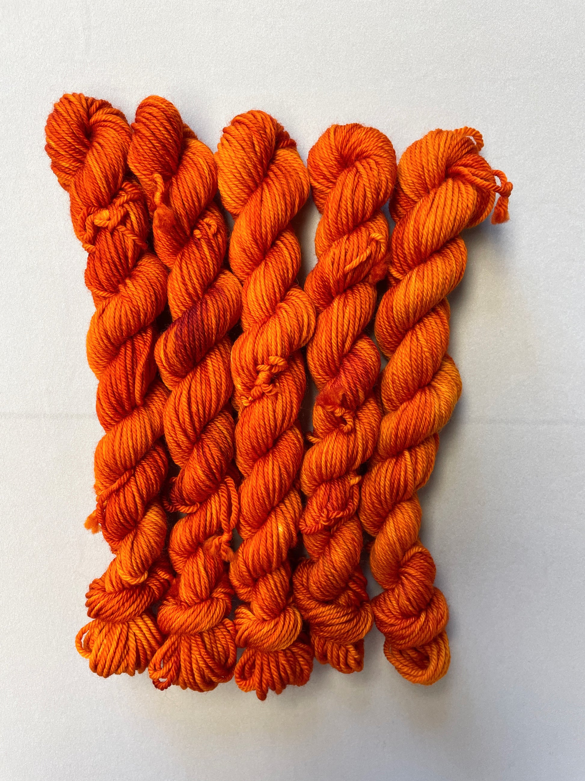 Zoomed in shot of 20g DK weight mini skeins in semi-solid colourway Saffron, a deep and intense orange colourway.