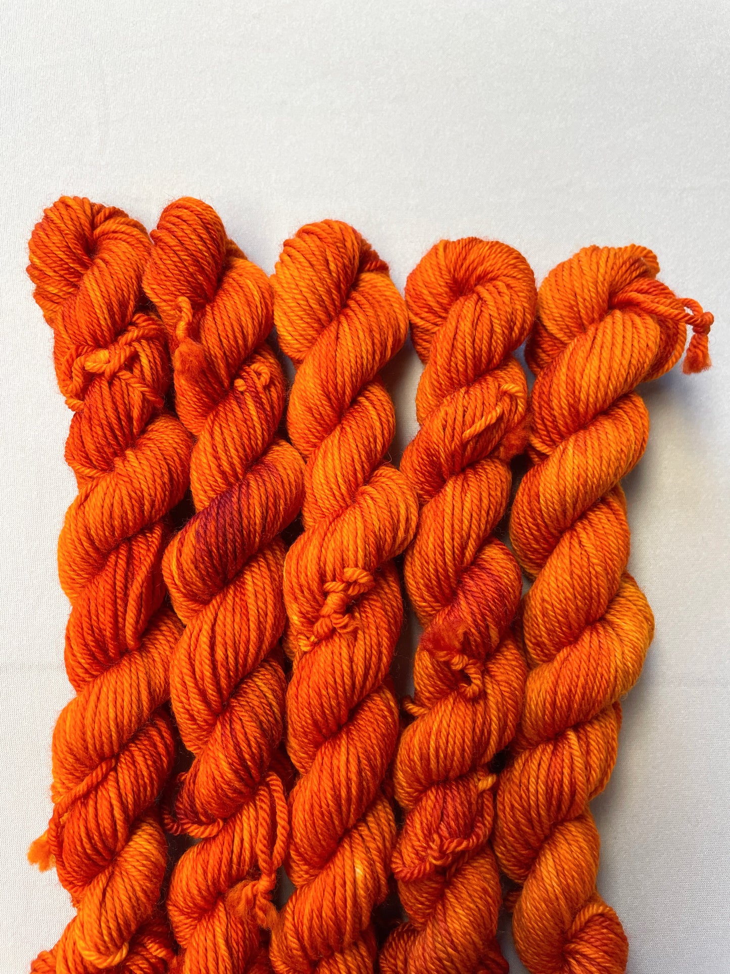 Close up shot of 20g DK weight mini skeins in semi-solid colourway Saffron, a deep and intense orange colourway.