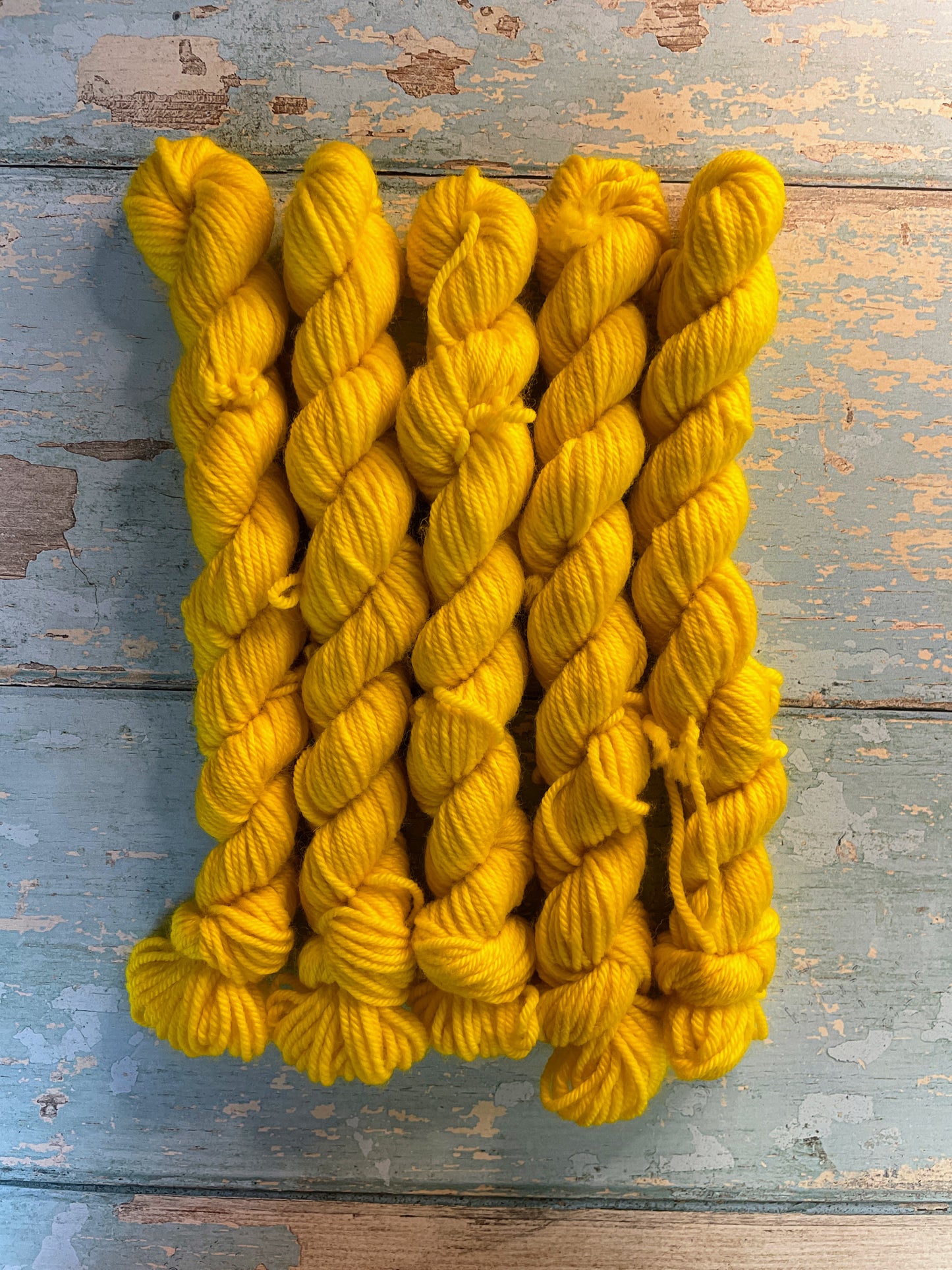 Zoomed in shot of DK weight mini skeins in the colourway Sunshine. This semi-solid colourway in shade Bright Yellow. 