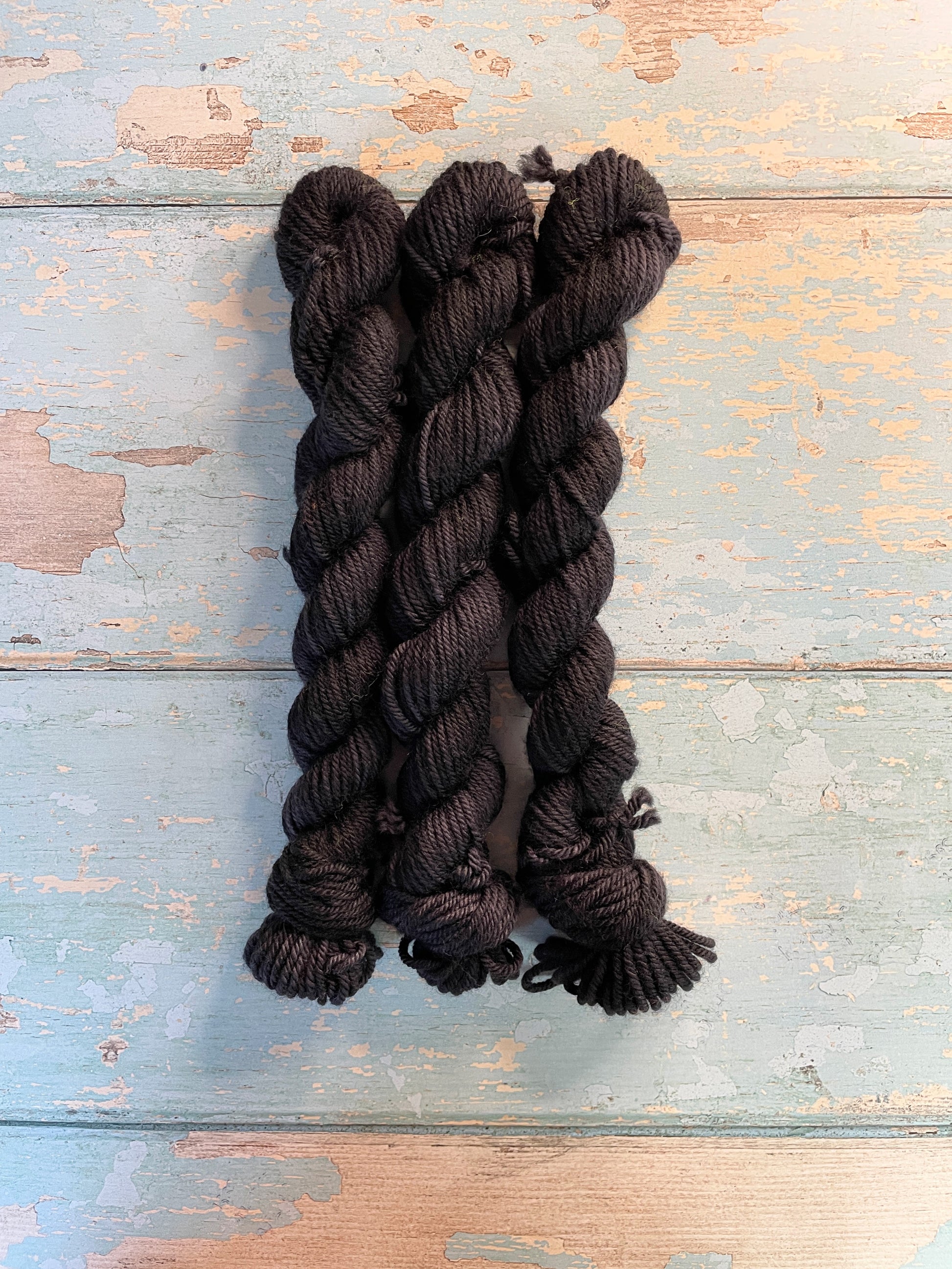 Full shot of 20g sock weight mini skeins in semi-solid colourway Black. This colourway is a deep, intense Black colour. 