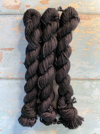 Zoomed in shot of 20g sock weight mini skeins in semi-solid colourway Black. This colourway is a deep, intense Black colour. 