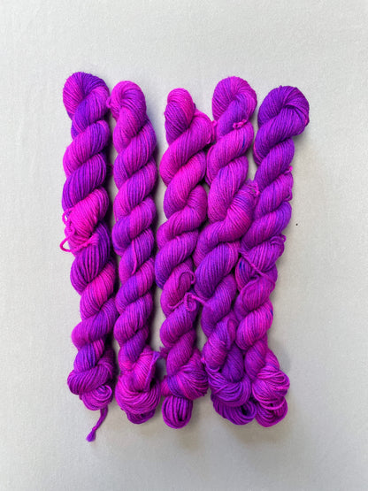 Full shot of 20g Sock weigh mini skeins in colourway Electric Purple. This colourway is an intense and bright purple that breaks into Neon Pink. Photographed on light grey background.