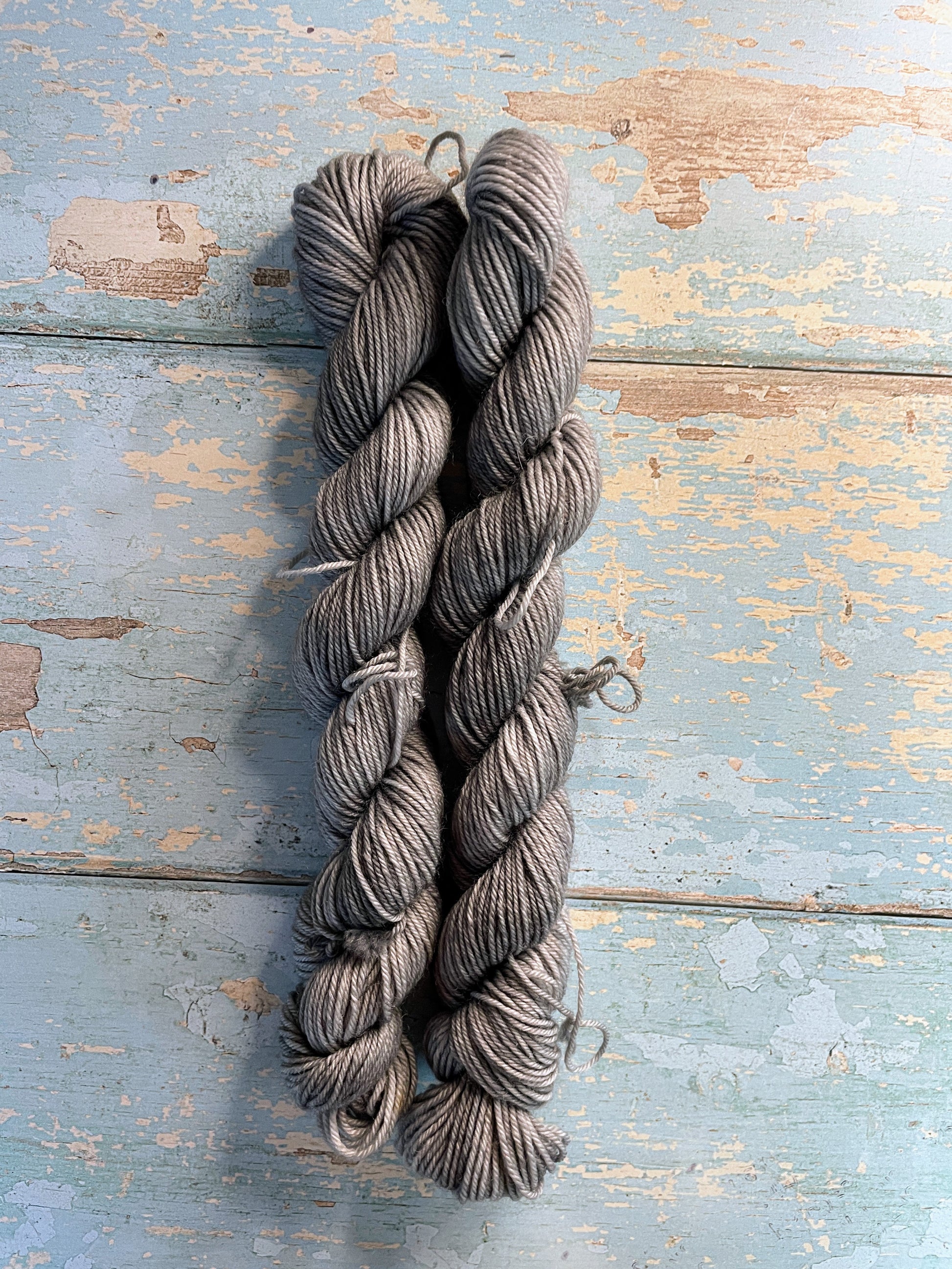 Full shot of 20g sock weight mini skeins in semi-solid colourway Grey. This colourway is a rich silver, grey colour.