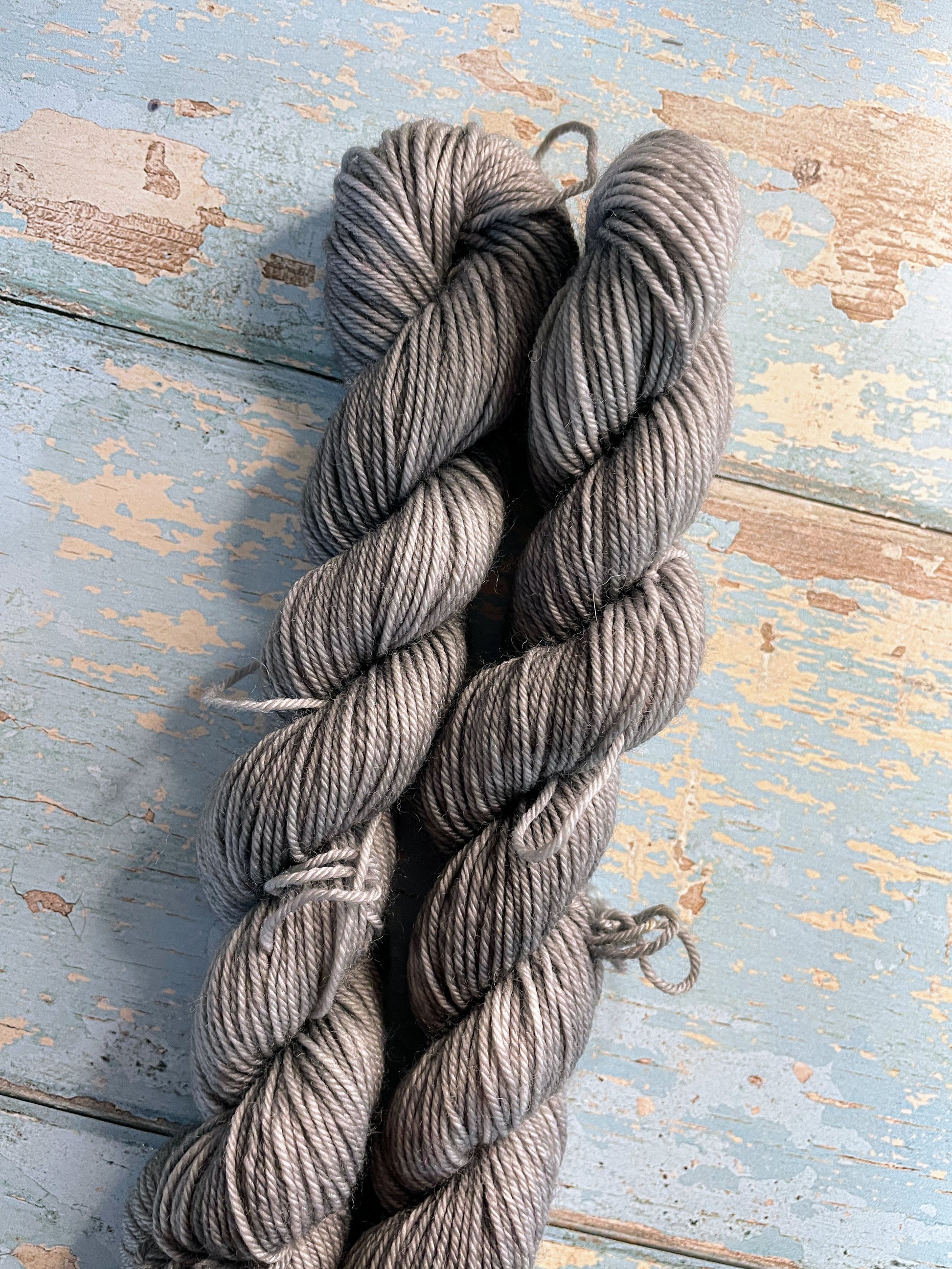 Close up shot of 20g sock weight mini skeins in semi-solid colourway Grey. This colourway is a rich silver, grey colour.