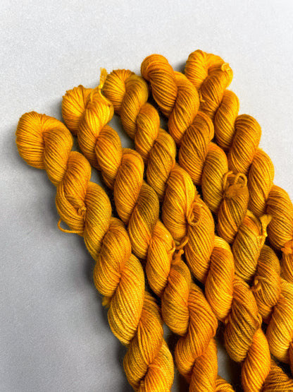 Hand-dyed Yarn 
5 x 20g, twisted, Sock mini skeins in colourway Hay Fields, photographed on a light grey background. This colourway is variegated with golden tones of Mustard, Golden Poppy and Saffron.