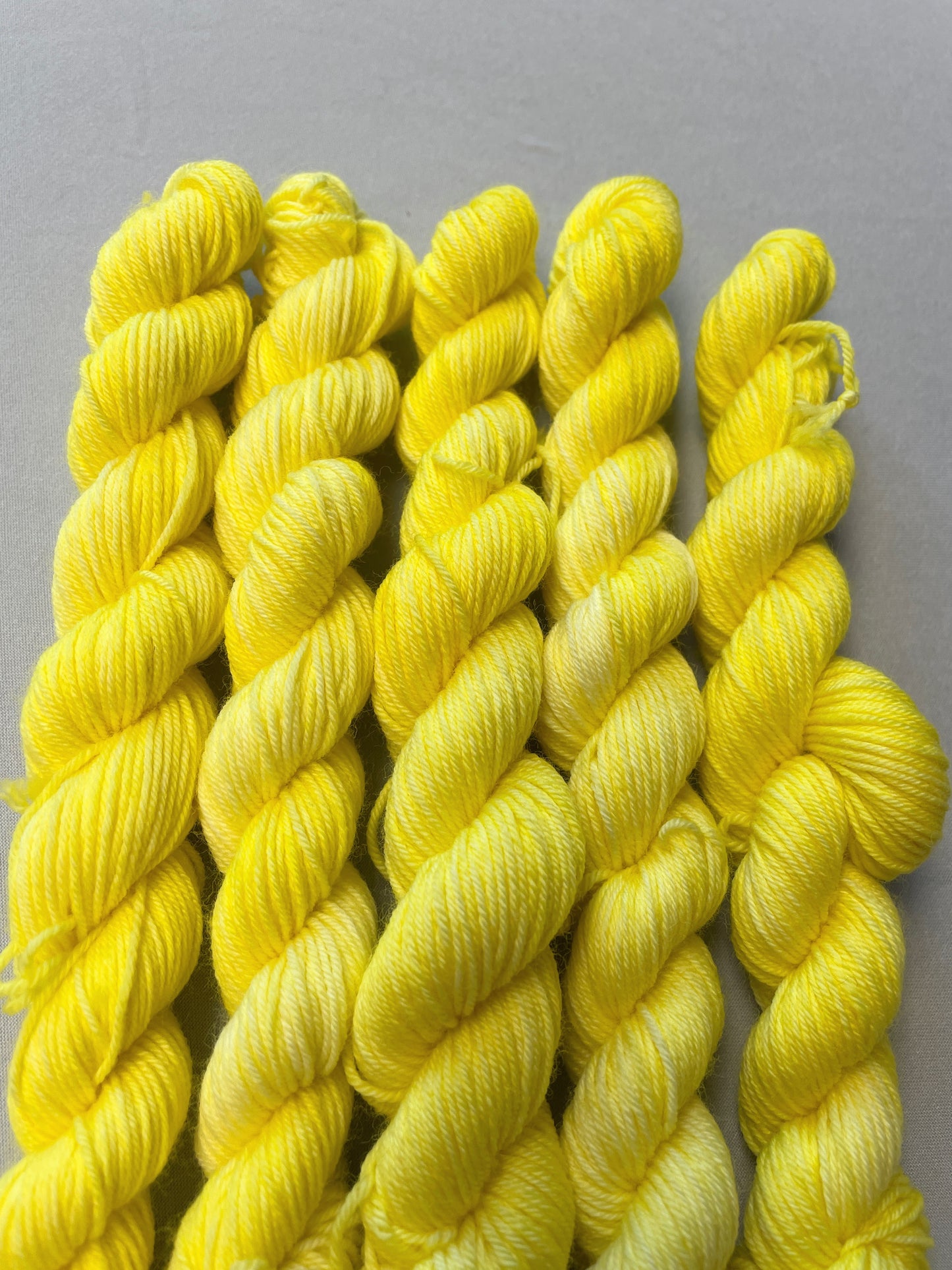 Close up shot of 20g Sock weight mini skeins in colourway Lemon. A semi-solid colourway of pale yellow colour. 