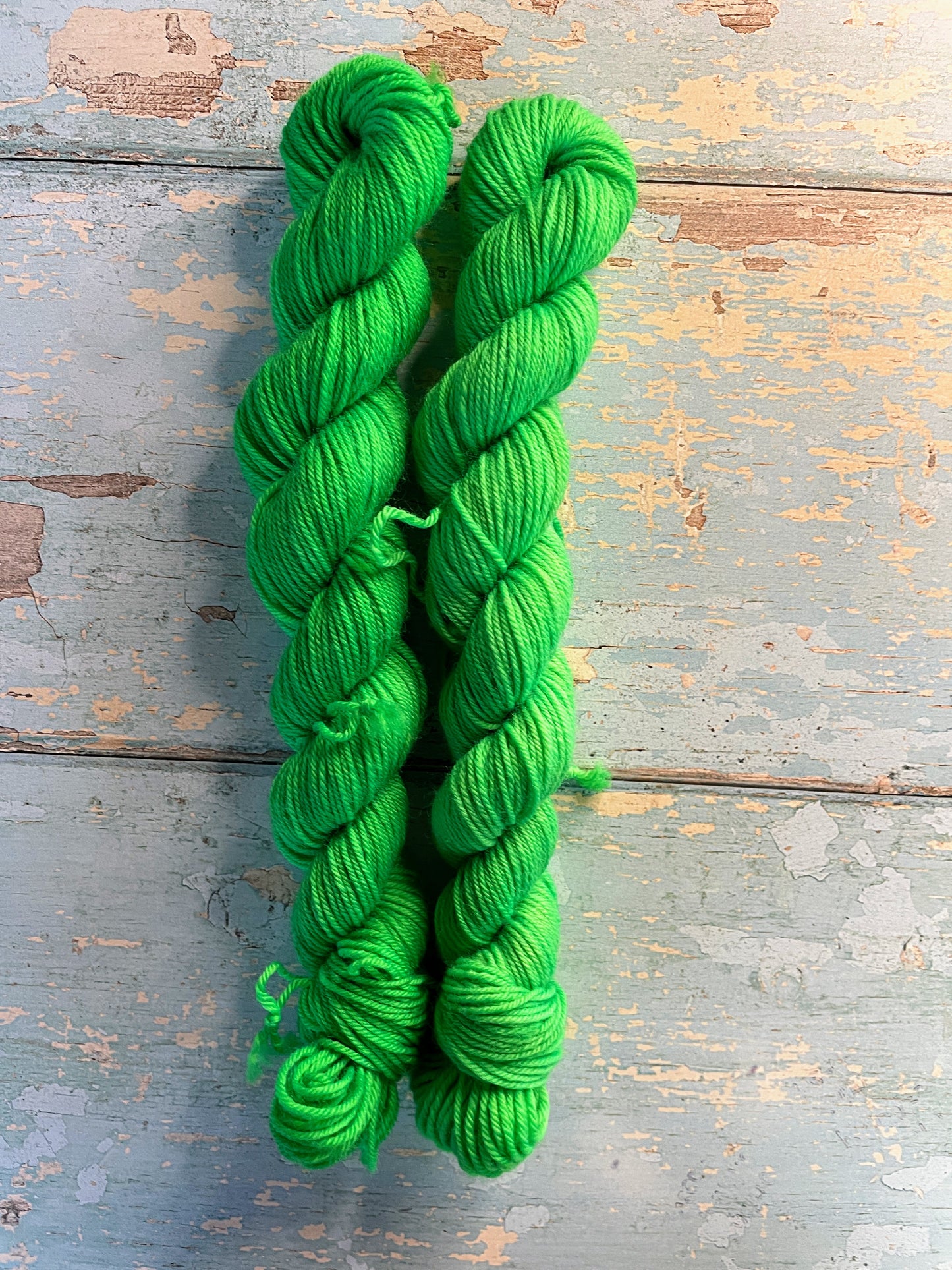 Full shot of 20g sock mini skeins in colourway Neon Green. This is a semi-solid colourway and will glow under U.V. light.