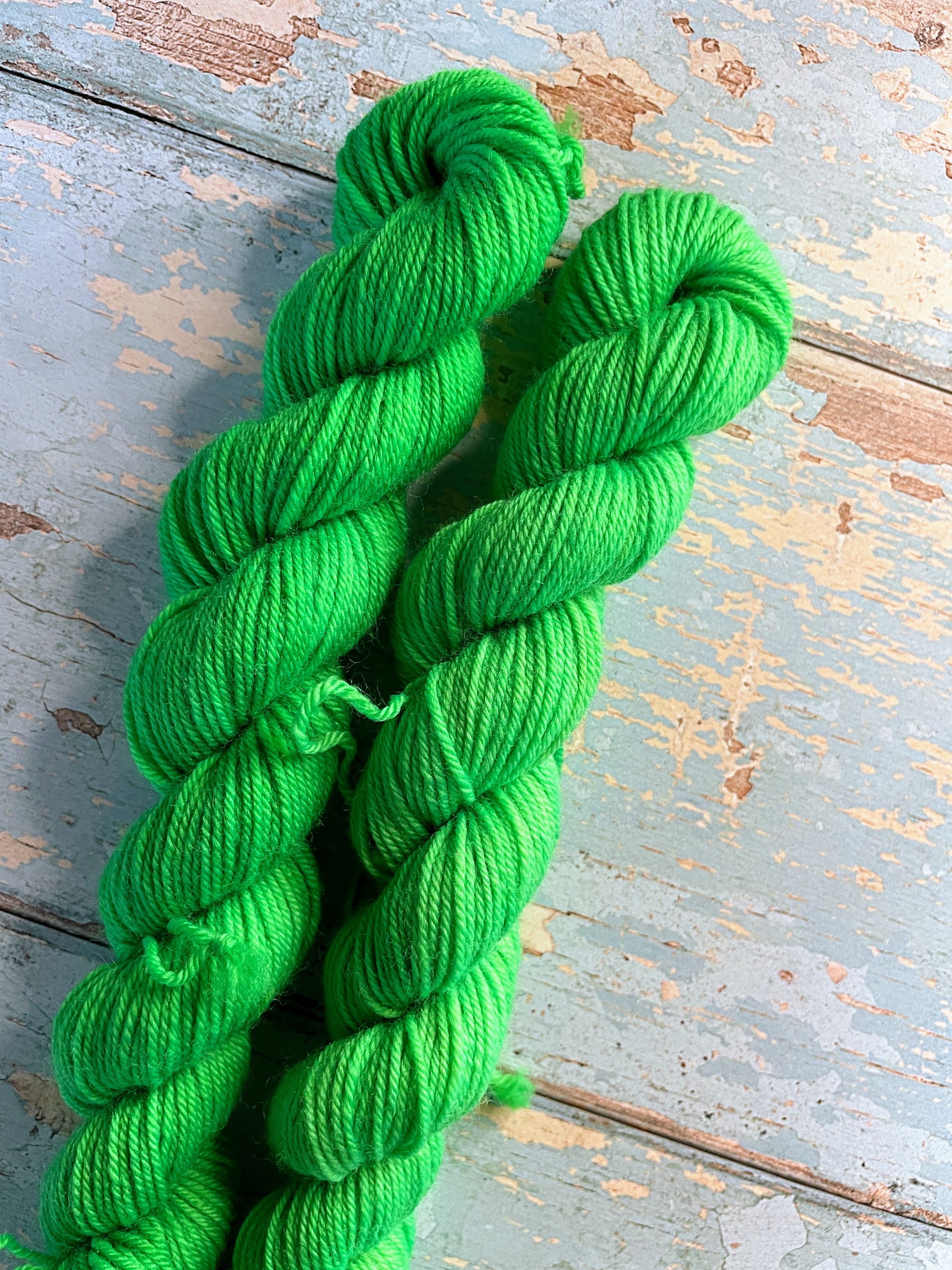 Close up shot of 20g sock mini skeins in colourway Neon Green. This is a semi-solid colourway and will glow under U.V. light.