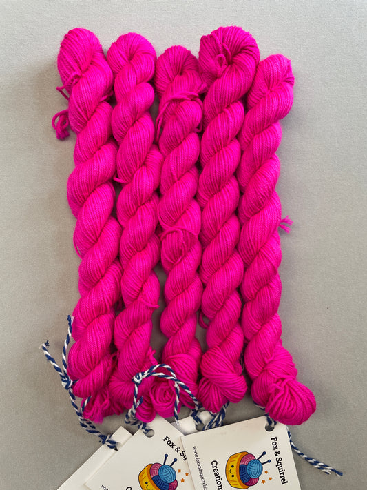 Full shot of 20g sock mini skeins in semi-solid colourway Neon Pink. This colourway glows under U.V. blue light and is as bright as a highlighter.