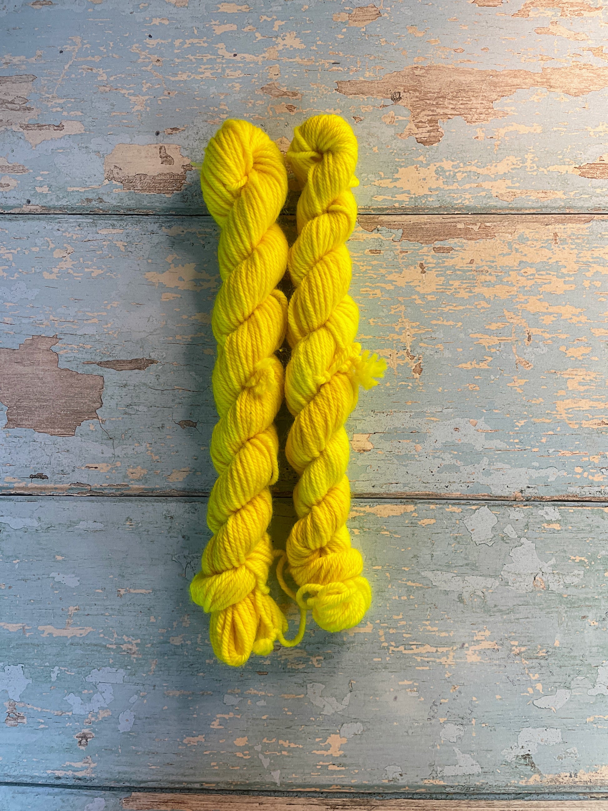 Full shot of 20g sock weight mini skeins in semi-solid colourway Neon Yellow. This colourway is an intense yellow colour, think highlighter, and will shine under U.V. light.