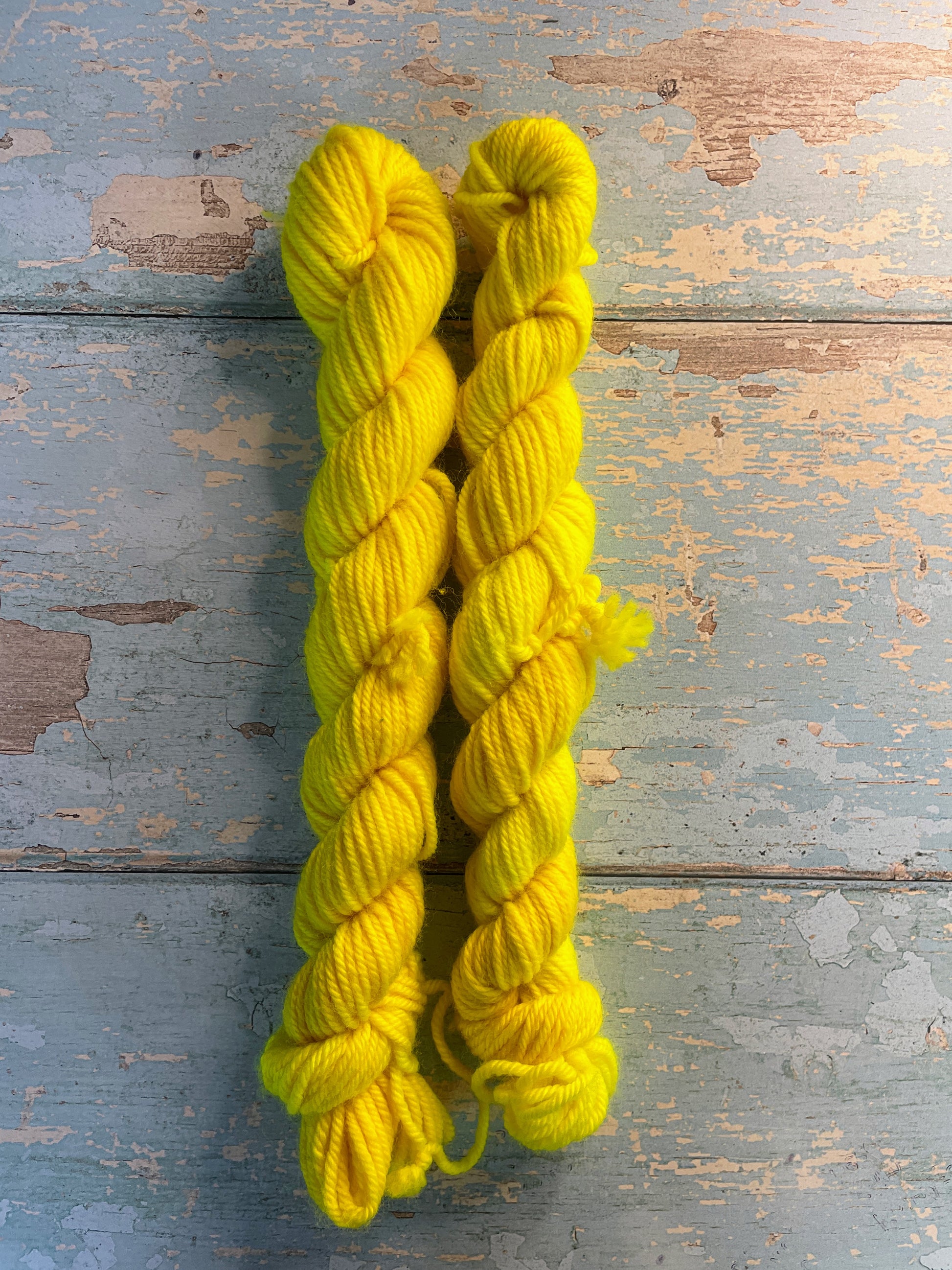 Zoomed in shot of 20g sock weight mini skeins in semi-solid colourway Neon Yellow. This colourway is an intense yellow colour, think highlighter, and will shine under U.V. light.