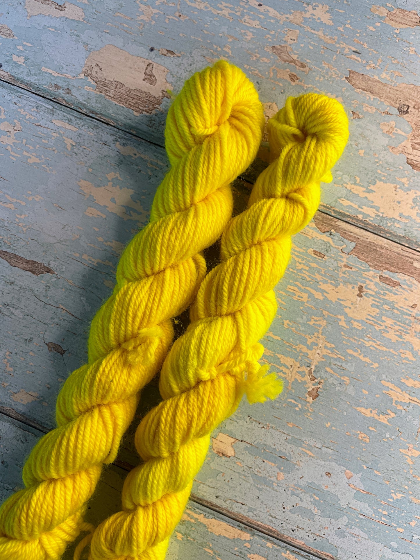 Close up shot of 20g sock weight mini skeins in semi-solid colourway Neon Yellow. This colourway is an intense yellow colour, think highlighter, and will shine under U.V. light.