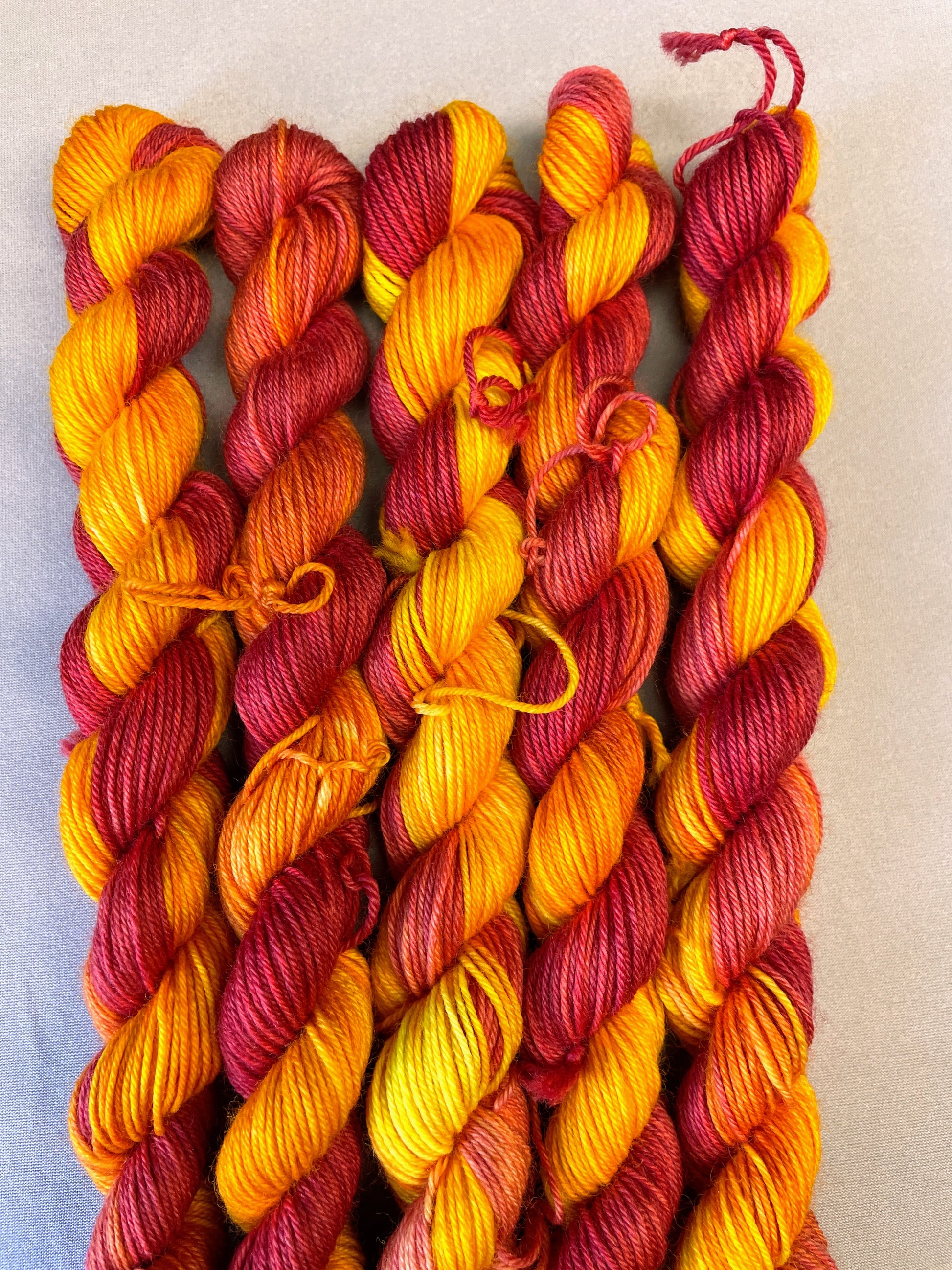 Hand-dyed Yarn
5 x 20g twisted, Sock mini skeins in colourway Phoenix, photographed on light grey background. This colourway is full of tones of Golden Poppy, Ruby Red and Saffron.