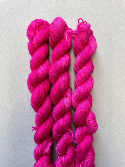 Close up shot of 20g sock weight mini skeins in colourway Pink. A semi-solid colourway in a bright pink shade. 