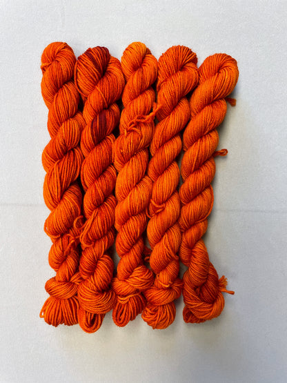 Zoomed in shot of 20g sock weight mini skeins in semi-solid colourway Saffron, a deep and intense orange colourway.