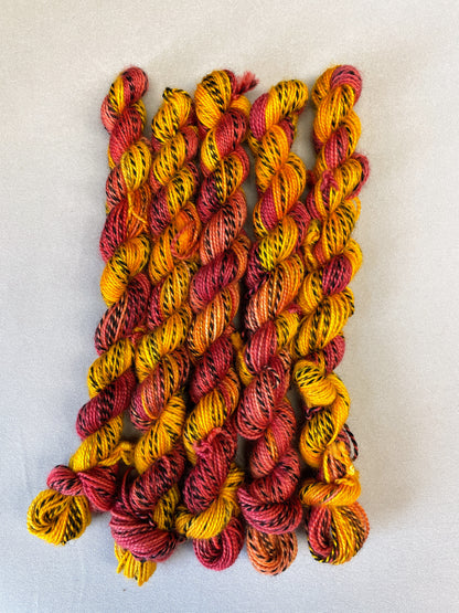 Hand-dyed Yarn
5 x 20g twisted, Zebra Sock mini skeins in colourway Phoenix, photographed on light grey background. This colourway is full of tones of Golden Poppy, Ruby Red and Saffron with the black and white strip running through it. 