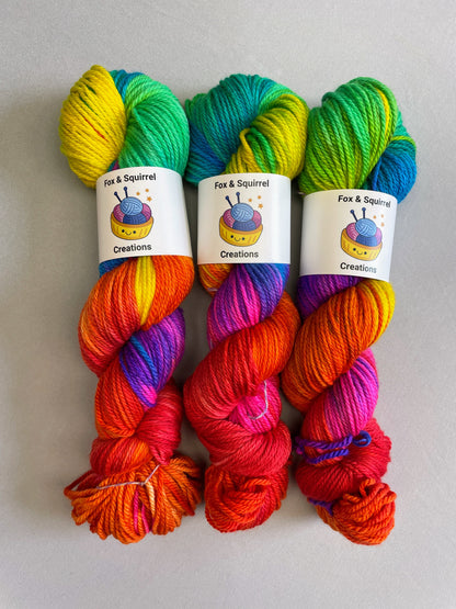 3 skeins of Hand-dyed Yarn in colourway Bright Rainbow on our Aran yarn base. This yarn base is 100% merino wool. The yarn contains 7 bright colours, sunshine, lava, ruby, apple, cyan, electric purple and neon pink and is photographed on a white background.  