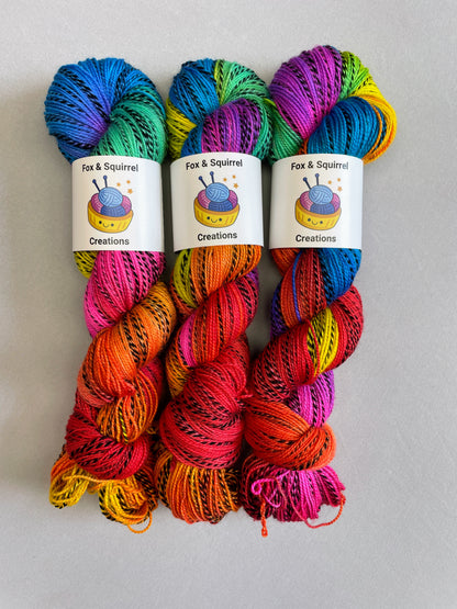 3 skeins of Hand-dyed Yarn in colourway Bright Rainbow on our Zebra Sock yarn base. The yarn contains 7 bright colours, sunshine, lava, ruby, apple, cyan, electric purple and neon pink and is photographed on a white background. 